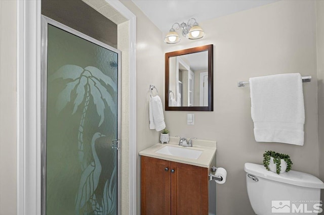 bathroom with a shower stall, toilet, and vanity