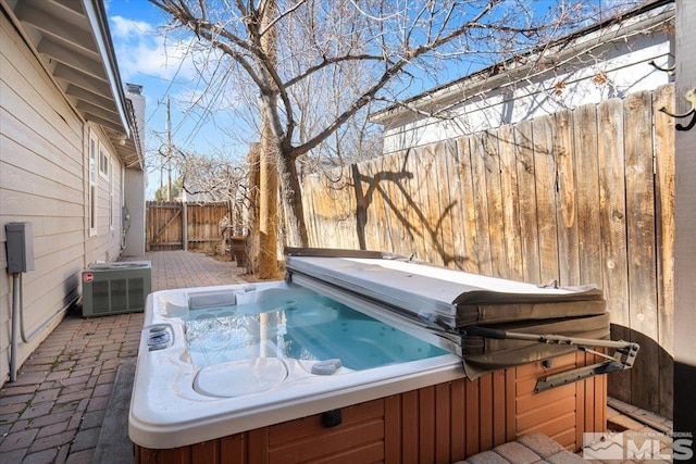 view of swimming pool with a fenced backyard, a hot tub, and central AC unit