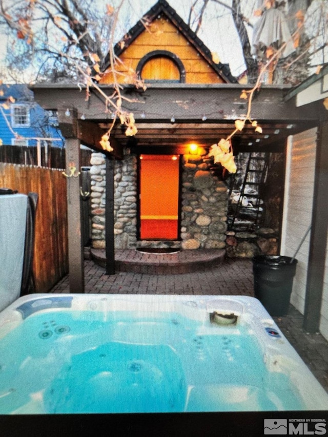 exterior space with an outdoor hot tub and fence