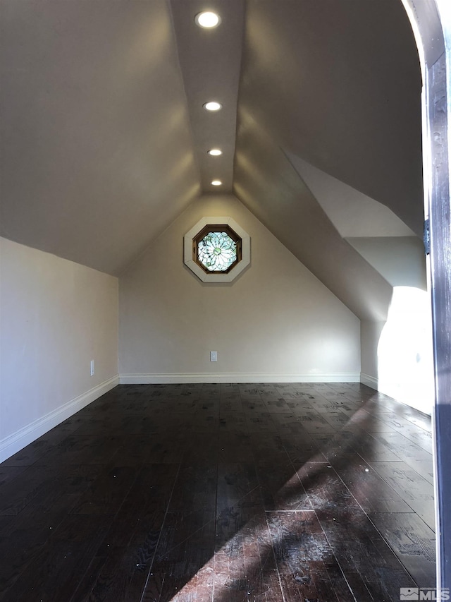 additional living space with arched walkways, baseboards, hardwood / wood-style floors, vaulted ceiling, and recessed lighting