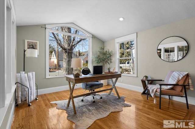 office area with light wood-style floors, baseboards, and vaulted ceiling