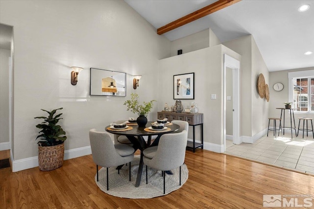 dining room featuring lofted ceiling with beams, baseboards, and wood finished floors