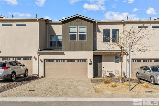 townhome / multi-family property with decorative driveway, board and batten siding, an attached garage, and stucco siding