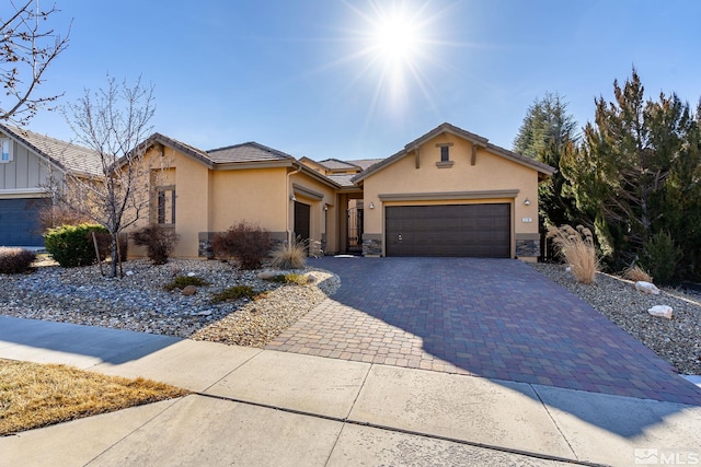 view of front facade with decorative driveway, a tile roof, stucco siding, a garage, and stone siding