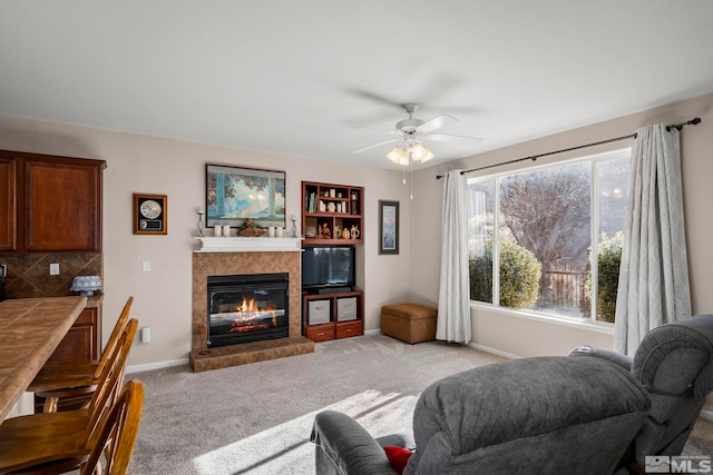 living area with light carpet, a fireplace, baseboards, and ceiling fan