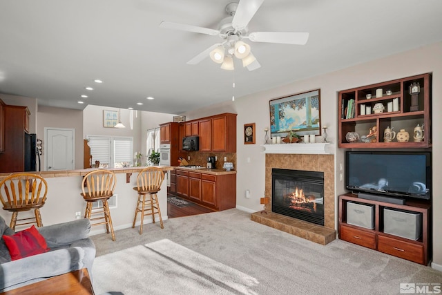 carpeted living area with a ceiling fan, recessed lighting, baseboards, and a tile fireplace