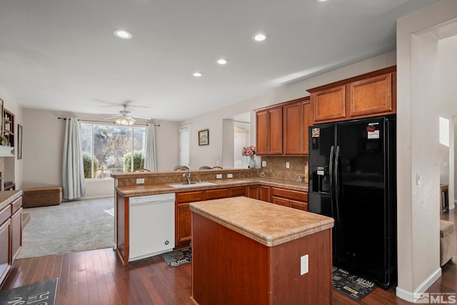 kitchen with a peninsula, a sink, black fridge, dishwasher, and brown cabinetry