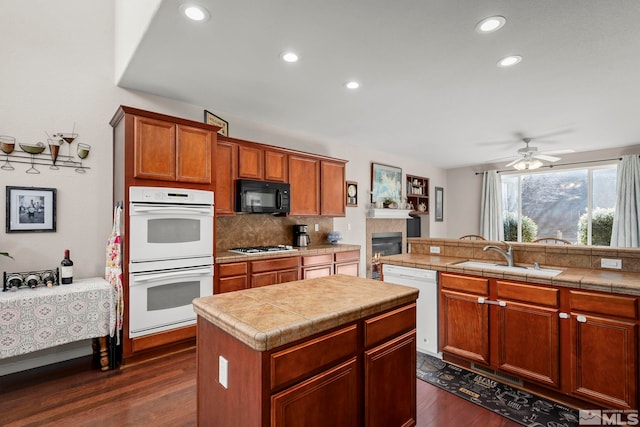 kitchen featuring white appliances, tasteful backsplash, dark wood-style flooring, a center island, and a sink