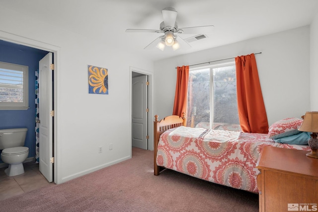 carpeted bedroom featuring ceiling fan, connected bathroom, visible vents, and baseboards