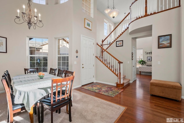 dining space with hardwood / wood-style flooring, stairs, baseboards, and an inviting chandelier