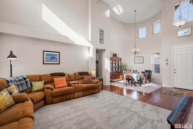 living area with baseboards, wood-type flooring, and a notable chandelier