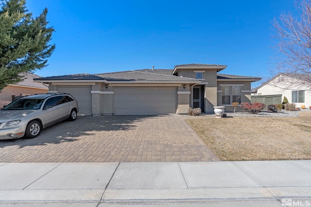 prairie-style home with a garage, decorative driveway, a tile roof, and stucco siding