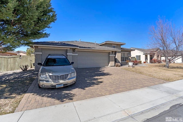 view of front of house with decorative driveway, fence, an attached garage, and stucco siding