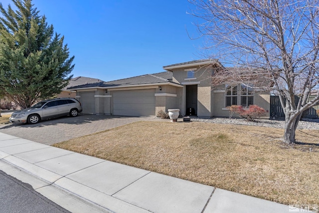 view of front of property with a garage, a front yard, decorative driveway, and stucco siding