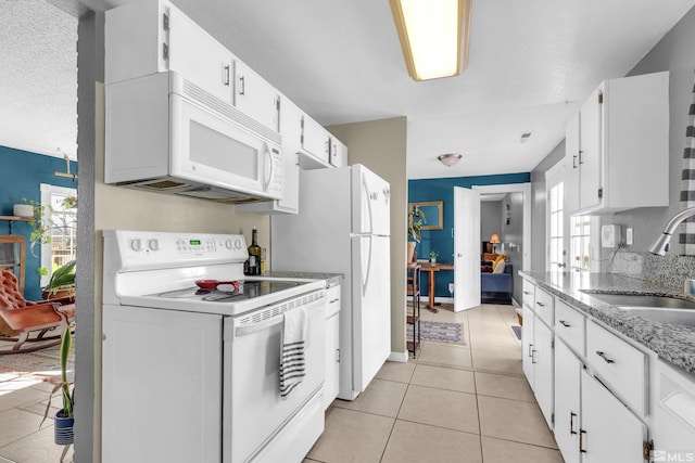 kitchen with white appliances, a healthy amount of sunlight, a sink, and light tile patterned floors