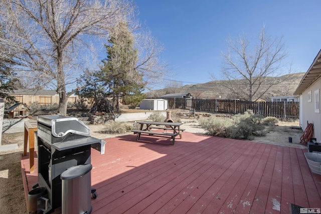 wooden deck with a shed, an outdoor structure, and fence