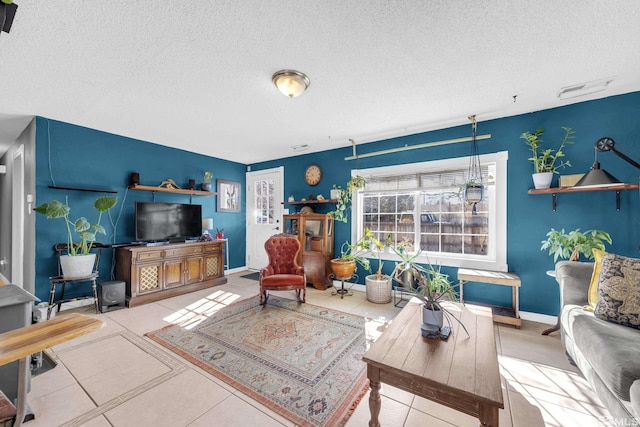 living room with visible vents, baseboards, a textured ceiling, and tile patterned floors