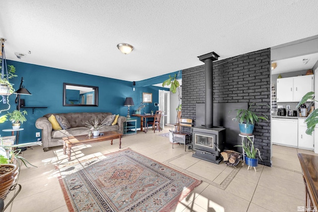 living area with a wood stove, light tile patterned floors, and a textured ceiling