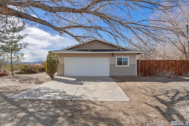 garage featuring driveway and fence