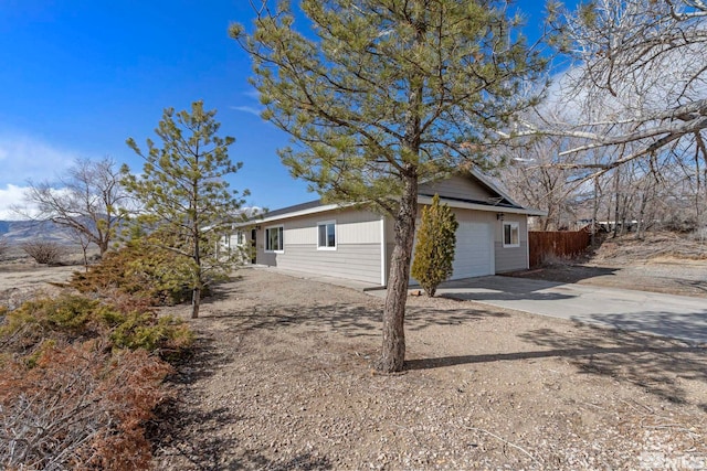 view of property exterior with a garage, driveway, and fence