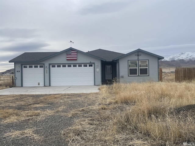 view of front facade featuring a garage, concrete driveway, fence, and a shingled roof