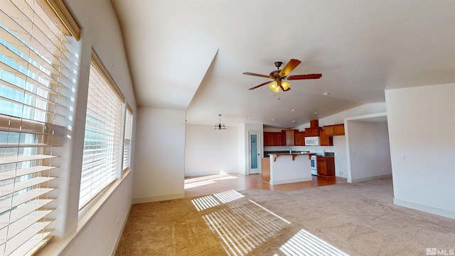 unfurnished living room with a ceiling fan, light carpet, vaulted ceiling, and baseboards