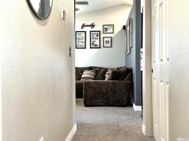 corridor with baseboards, carpet floors, and a textured wall