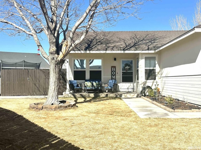 property entrance with stucco siding, a shingled roof, and fence