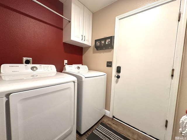 clothes washing area with cabinet space, wood finished floors, and washer and clothes dryer