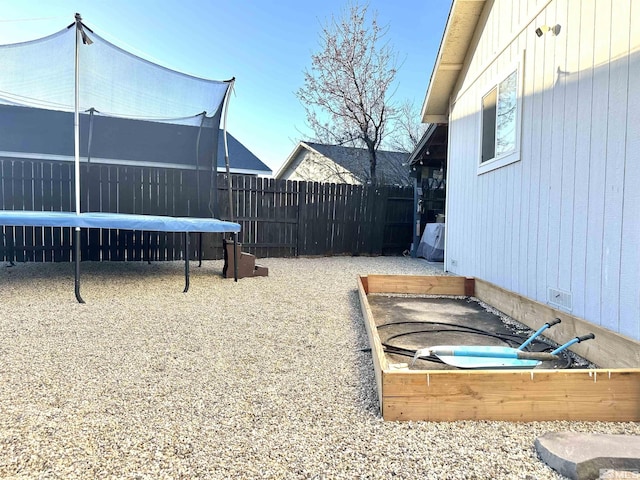 view of yard featuring a trampoline and fence