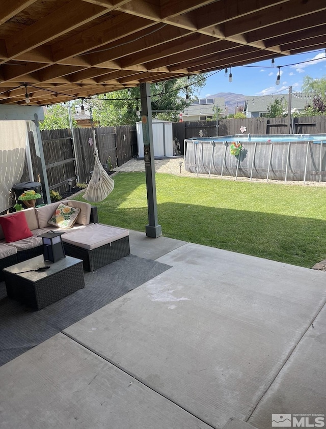 view of patio / terrace with an outdoor living space, a storage unit, a fenced backyard, and a fenced in pool