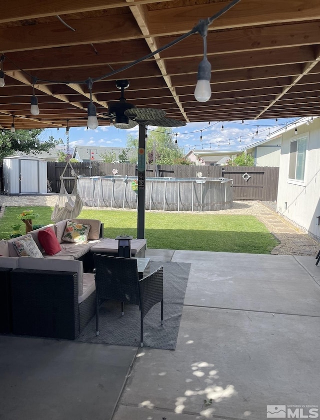 view of patio with an outdoor living space, a fenced in pool, a storage unit, and fence