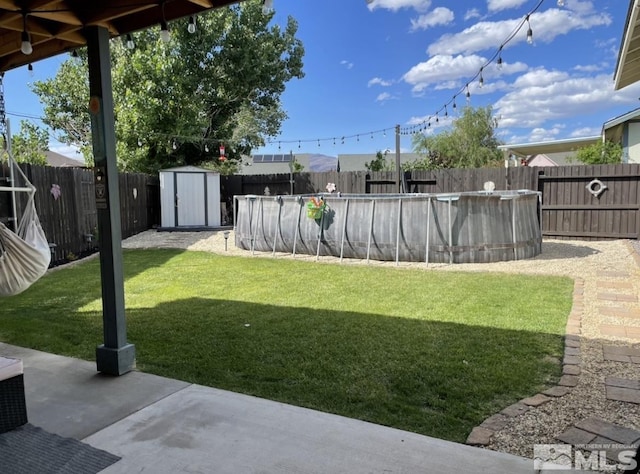 view of yard with an outbuilding, a storage unit, a fenced backyard, and a fenced in pool