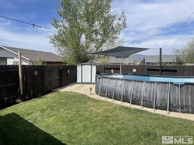 view of yard with an outbuilding, a fenced in pool, a storage shed, and a fenced backyard