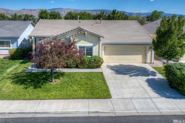 ranch-style house featuring concrete driveway, a tiled roof, an attached garage, a mountain view, and a front yard