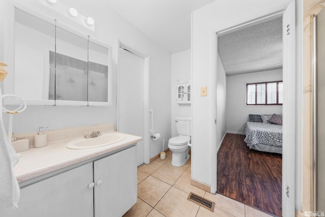 bathroom featuring a textured ceiling, tile patterned flooring, toilet, vanity, and visible vents