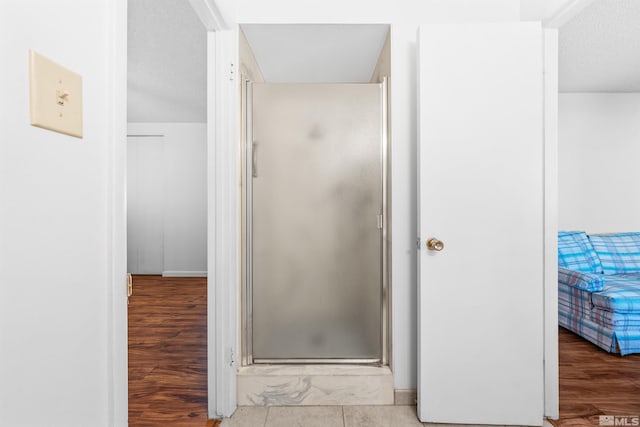 ensuite bathroom with a shower stall, connected bathroom, and wood finished floors