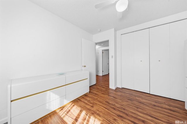 unfurnished bedroom featuring a textured ceiling, ceiling fan, a closet, and wood finished floors