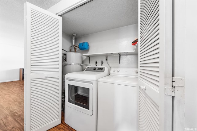 washroom with a textured ceiling, laundry area, wood finished floors, and washing machine and dryer