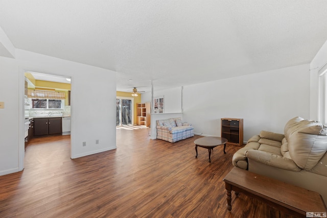 living room with a textured ceiling, beverage cooler, wood finished floors, a ceiling fan, and baseboards