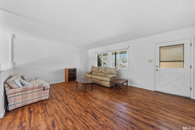 living room with a textured ceiling, baseboards, and wood finished floors