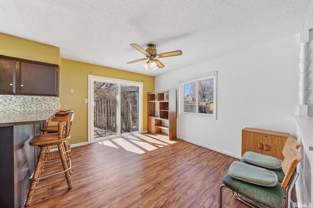 living area with plenty of natural light, baseboards, ceiling fan, and wood finished floors