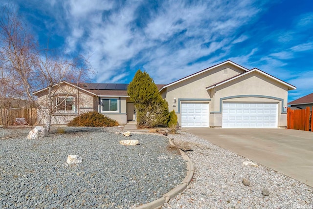 ranch-style home featuring a garage, solar panels, fence, driveway, and stucco siding