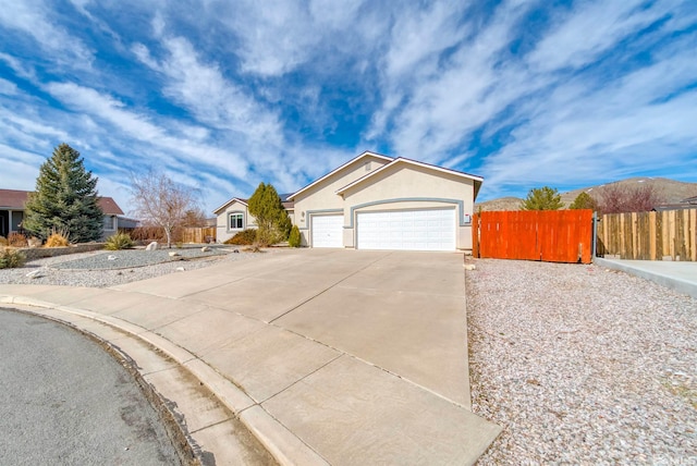 view of front of property with driveway, an attached garage, fence, and stucco siding