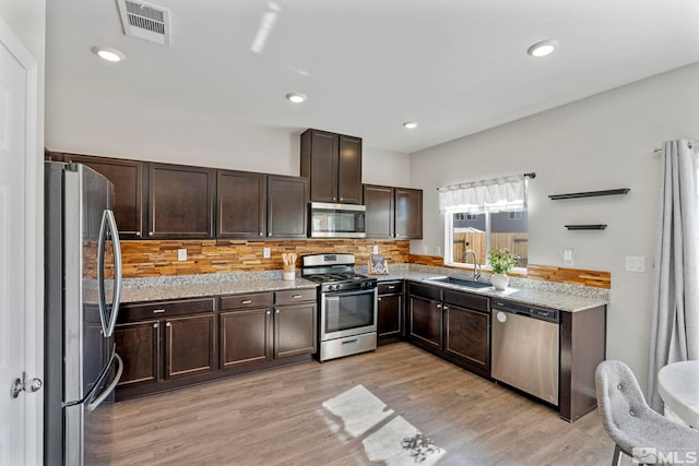 kitchen with appliances with stainless steel finishes, visible vents, a sink, and dark brown cabinets