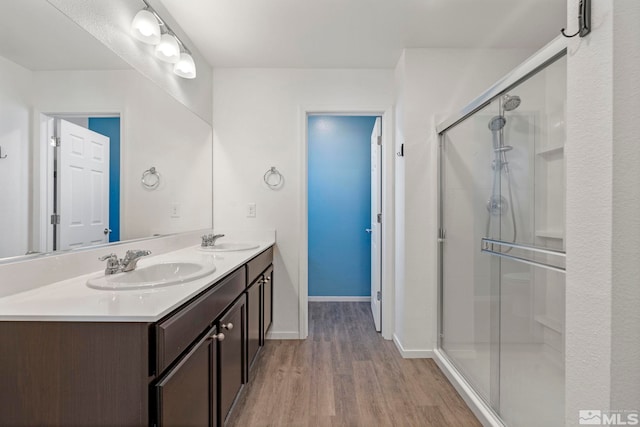 bathroom with a sink, a shower stall, and wood finished floors