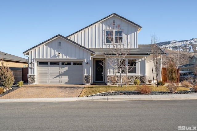 view of front of property featuring board and batten siding, decorative driveway, fence, and an attached garage