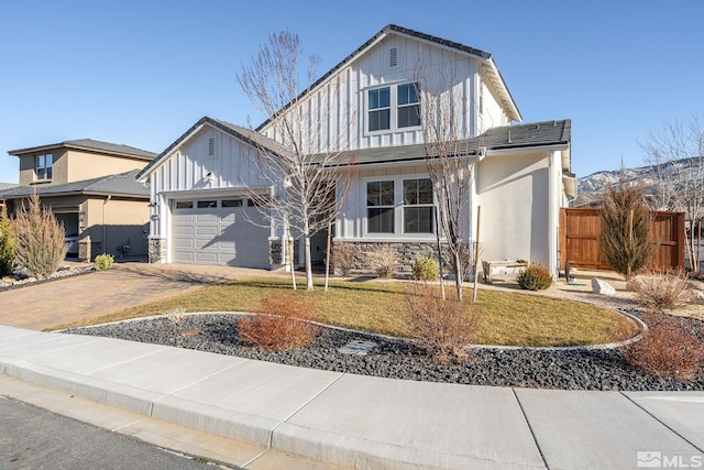 view of front facade featuring an attached garage, fence, decorative driveway, a front lawn, and board and batten siding