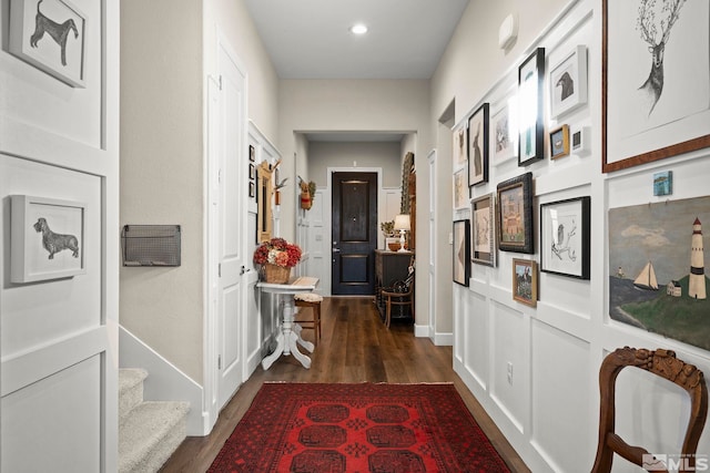 corridor with dark wood-type flooring, stairway, and recessed lighting