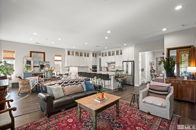 living area with dark wood-type flooring and recessed lighting